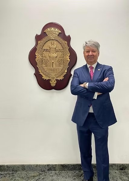 Pedro Luis García de los Huertos Vidal, notario de Ferrol, junto al escudo de Ferrol en el despacho